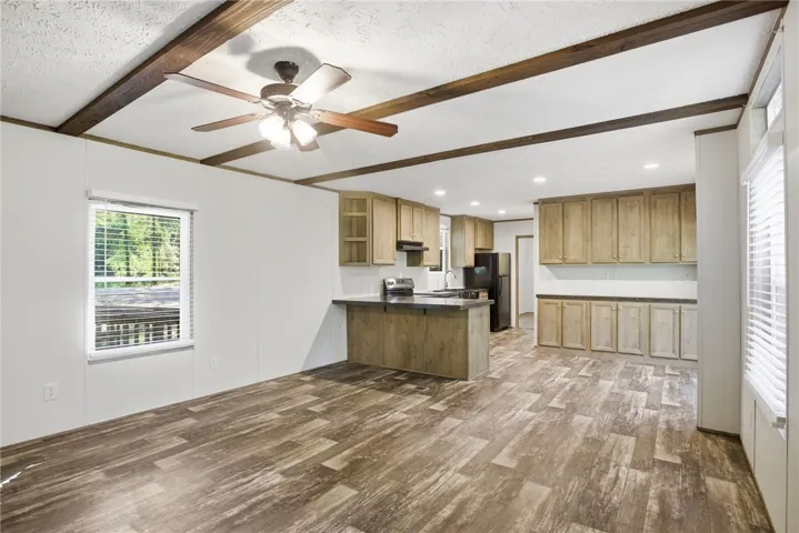 A well-lit kitchen and living area features exposed wood beams and durable flooring, creating an inviting atmosphere.
