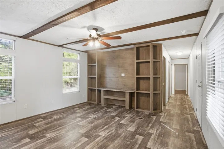 A well-lit living area showcases a built-in media center and durable wood-look flooring.
