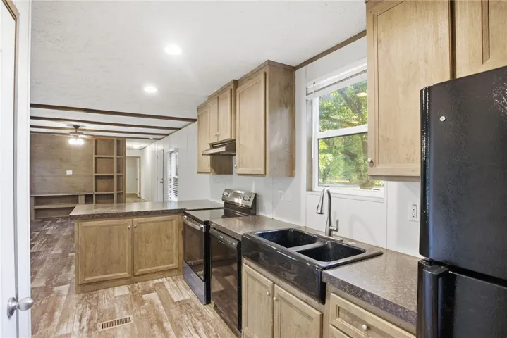 A well-equipped kitchen boasts a black farmhouse sink and abundant cabinetry, overlooking the living area.