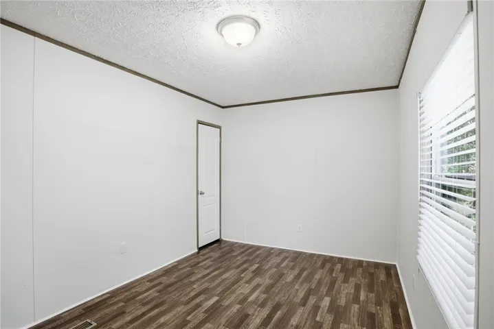 A well-proportioned room with durable wood-look flooring and a window offering natural light.