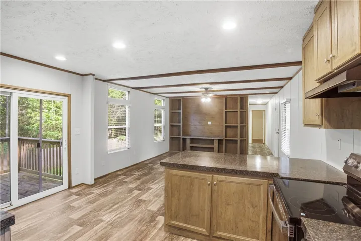 This airy open-concept living space features warm wood-look flooring and built-in shelving, seamlessly connecting to a private deck.