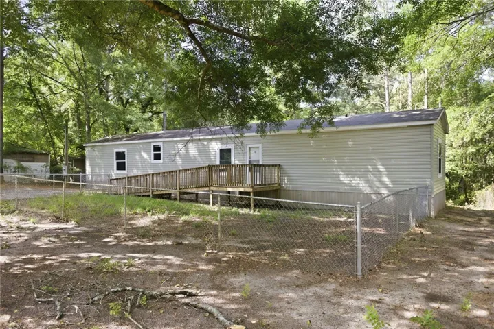 A ramped deck offers accessible entry to this siding-clad residence nestled among mature trees.