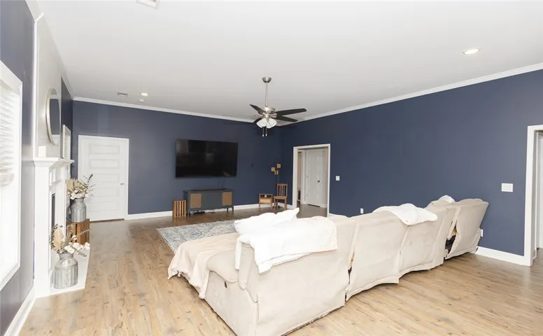 A spacious living area features hardwood flooring, a fireplace, and elegant crown molding.