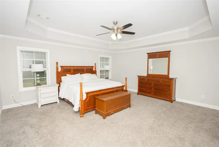 Step into comfort with this primary bedroom, featuring a tray ceiling and plush carpeting throughout.