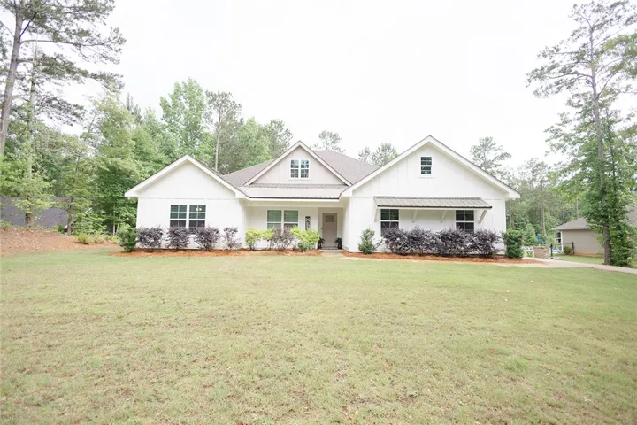 White siding and a neutral roof create a harmonious facade amidst a verdant landscape.