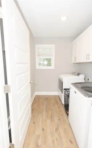 A well-lit laundry room offers ample space for chores and overhead storage cabinetry.