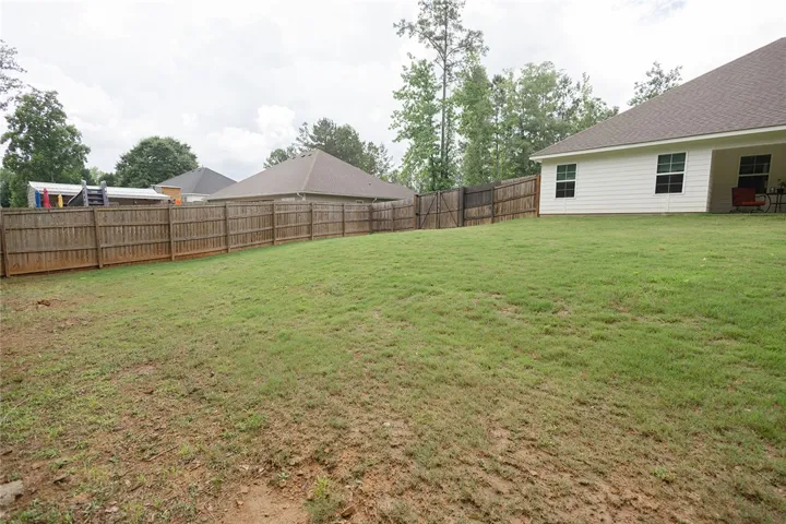 A spacious backyard provides ample green space, fully enclosed by a robust wooden privacy fence.