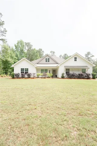 A classic white home, framed by lush greenery, presents inviting curb appeal.