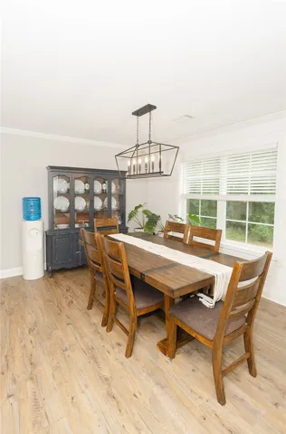 A warm dining area boasts hardwood-style flooring and a sophisticated light fixture.
