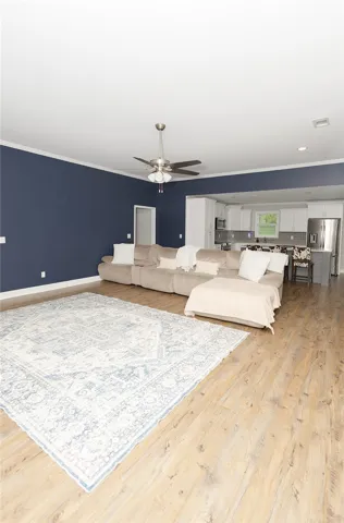 An open-concept living area flows seamlessly into the kitchen, showcasing durable wood flooring.