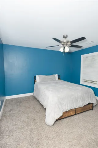 A vibrant room offers comfortable carpeting and a cooling ceiling fan for year-round comfort.