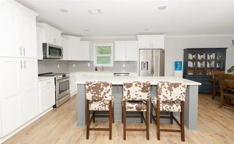 A well-appointed kitchen features stainless steel appliances, a generous island with seating, and wood-look flooring.