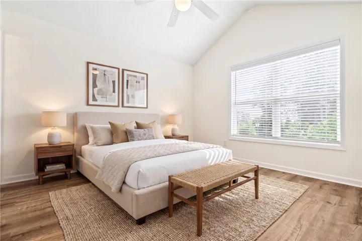 A naturally illuminated bedroom offers vaulted ceilings and warm wood flooring for comfortable living.