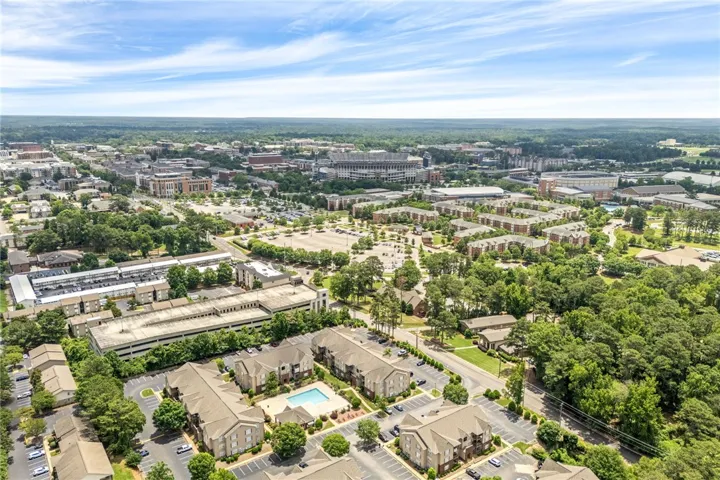 An aerial panorama reveals a dynamic residential and commercial landscape, nestled among lush, mature trees.
