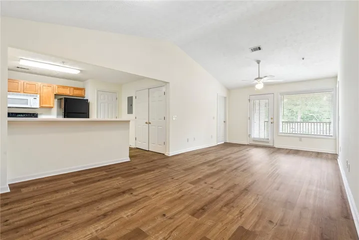 A harmonious blend of kitchen and living space, boasting warm flooring and a high vaulted ceiling.