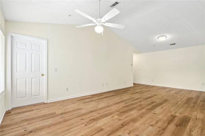 A well-lit area features wide plank flooring and a vaulted ceiling.