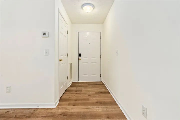 A welcoming entryway features rich hardwood flooring and a clean white door, setting a neutral tone.