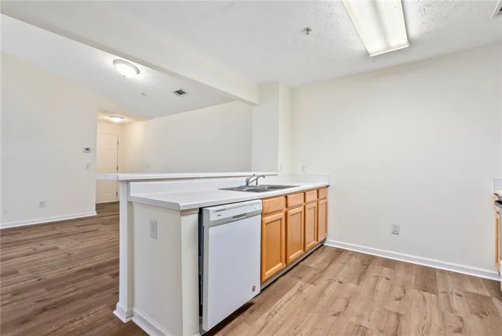 A compact kitchen with practical countertops, ample cabinetry, and rich wood flooring.
