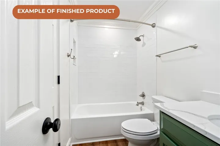 White subway tile surrounds a sleek tub and shower, complemented by a vibrant green vanity and pristine white countertop.