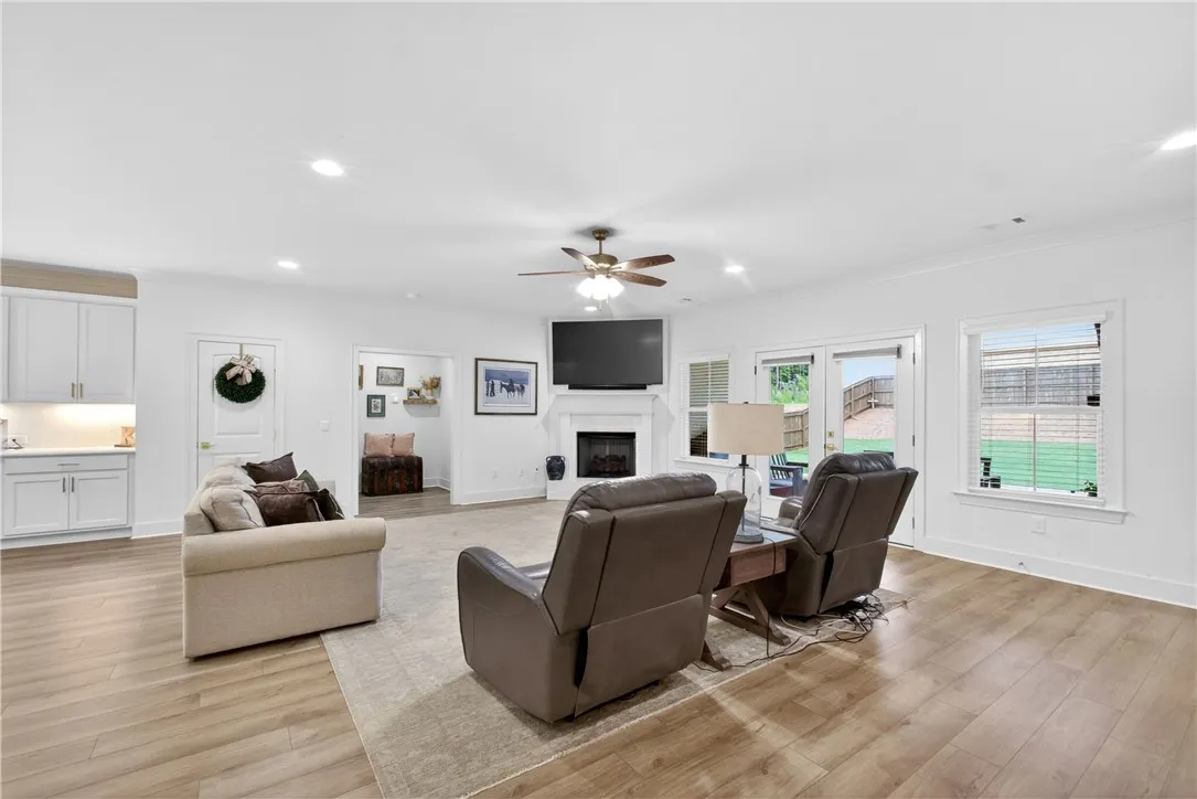 Sun-filled living space flows effortlessly to a private yard, featuring light-toned LVP flooring and a cozy fireplace.