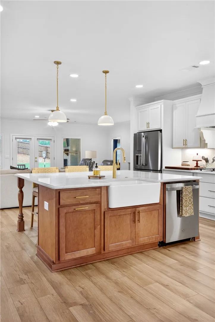 A grand central island with a farmhouse sink anchors this open-concept kitchen with warm LVP flooring.