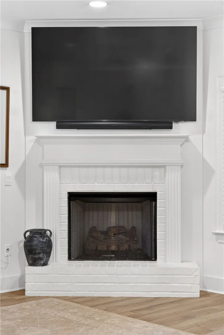 A classic fireplace with a white mantel and brick hearth anchors this inviting space.