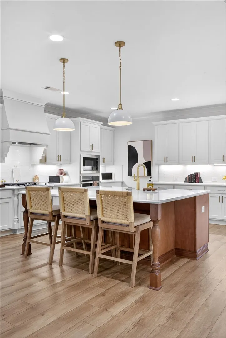 A well-appointed kitchen features a large central island, overhead pendant lights, and LVP flooring.