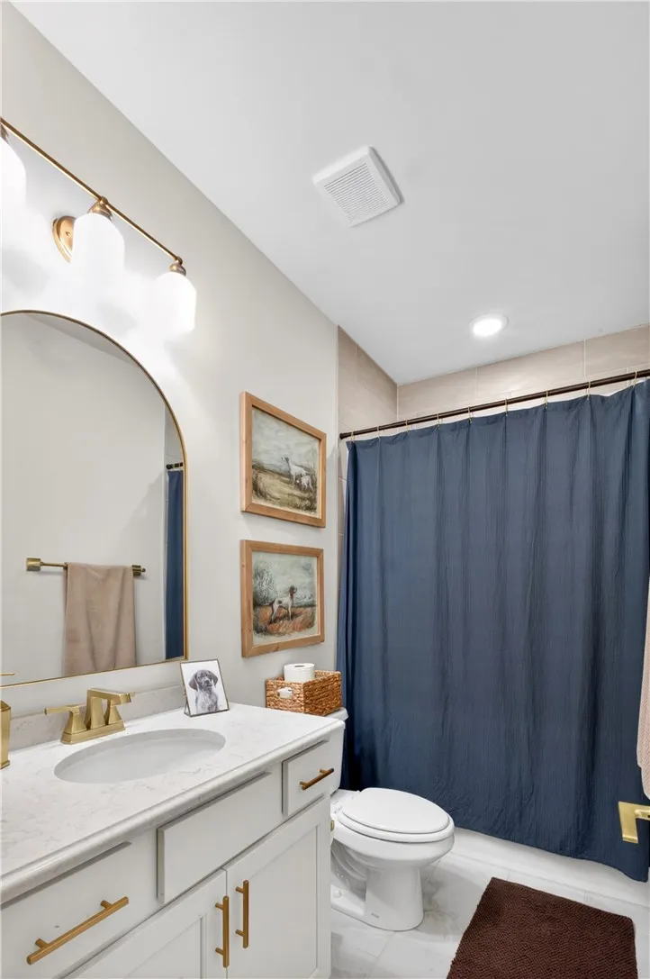 A clean, functional bathroom features a modern vanity with elegant hardware that compliments the ceramic tile shower surround and flooring.