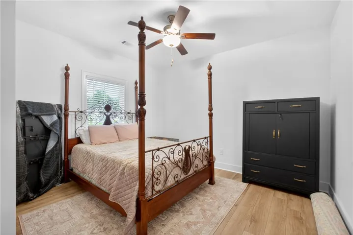 A well-lit bedroom features LVP floors and a window with blinds, creating a calm and inviting atmosphere.