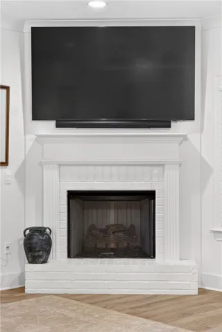 A classic fireplace with a white mantel and brick hearth anchors this inviting space.