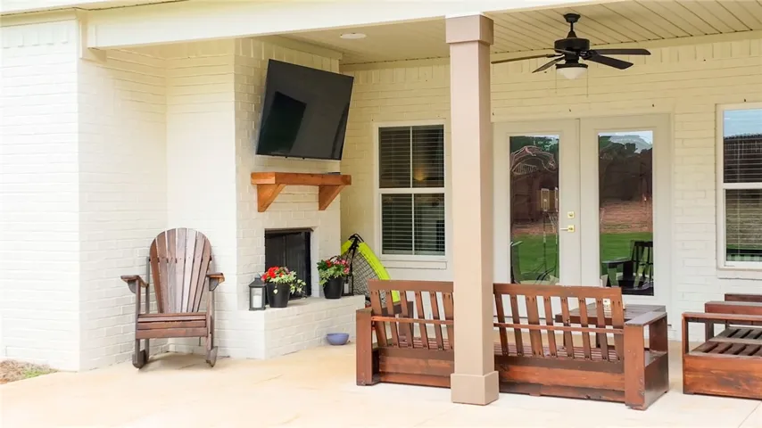 A welcoming outdoor living space features a fireplace, ceiling fan, and access to the verdant yard.