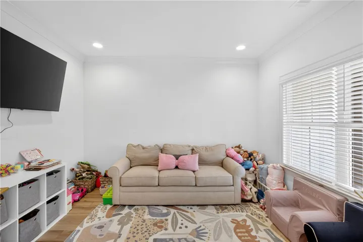 Recessed lighting illuminates this versatile living space with LVP flooring and natural light.
