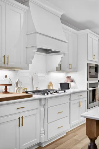 A well-appointed kitchen features a gas range and built-in appliances, accented by gleaming countertops and light cream colored cabinetry.