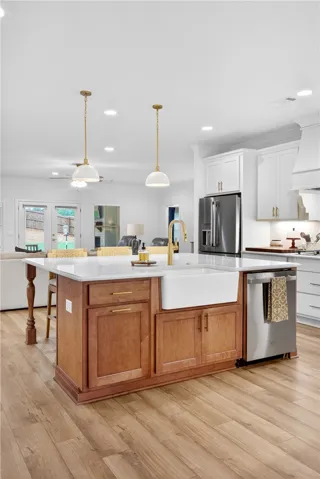 A grand central island with a farmhouse sink anchors this open-concept kitchen with warm LVP flooring.