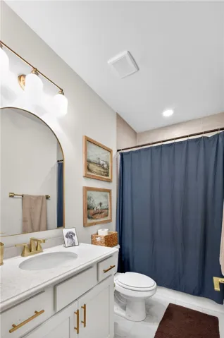 A clean, functional bathroom features a modern vanity with elegant hardware that compliments the ceramic tile shower surround and flooring.