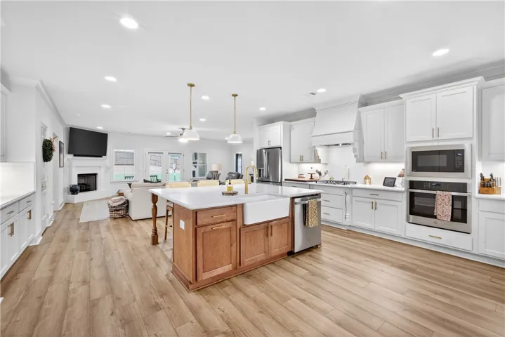 A grand central island anchors this naturally illuminated open-concept kitchen with abundant cabinetry and LVP flooring.
