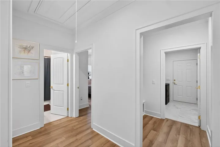 A well-lit hallway with natural wood-look LVP flooring leads to several rooms.