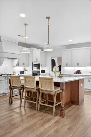 A well-appointed kitchen features a large central island, overhead pendant lights, and LVP flooring.