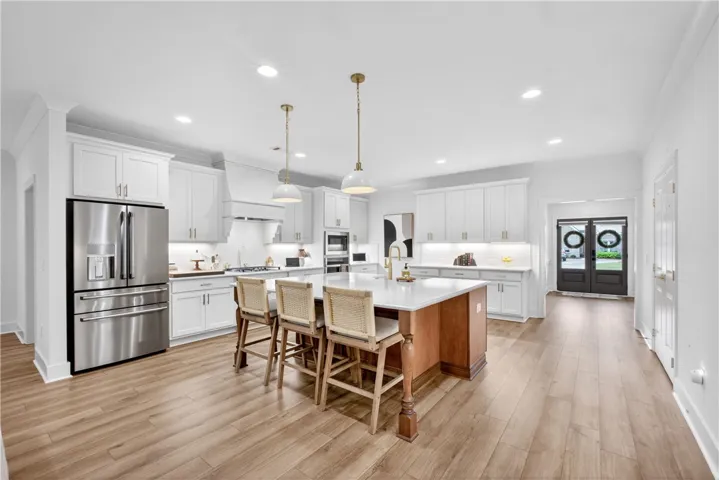 A well-lit kitchen featuring a spacious island, pendant lights, and stainless steel appliances.
