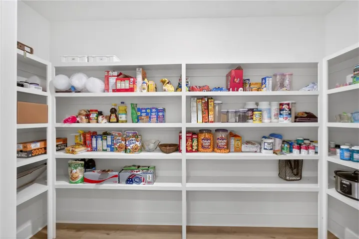 Ample, wood shelving provides extensive storage for kitchen essentials in this walk-in pantry.