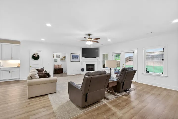 Sun-filled living space flows effortlessly to a private yard, featuring light-toned LVP flooring and a cozy fireplace.