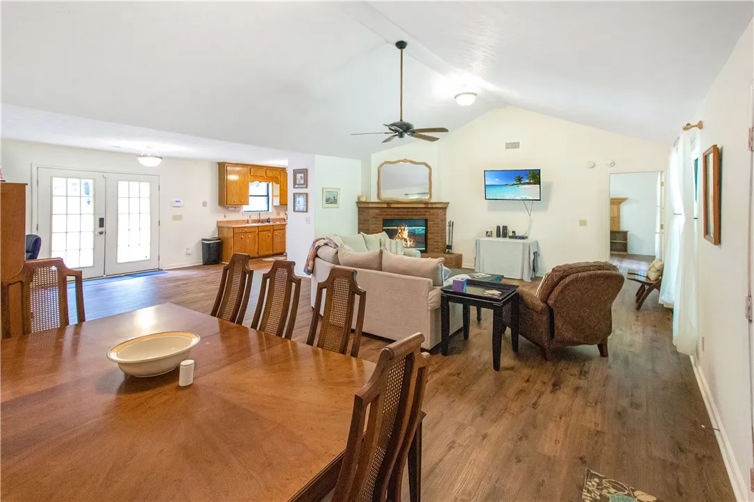 A welcoming great room, featuring a cozy brick fireplace and rich wood flooring, seamlessly connects to a classic kitchen.