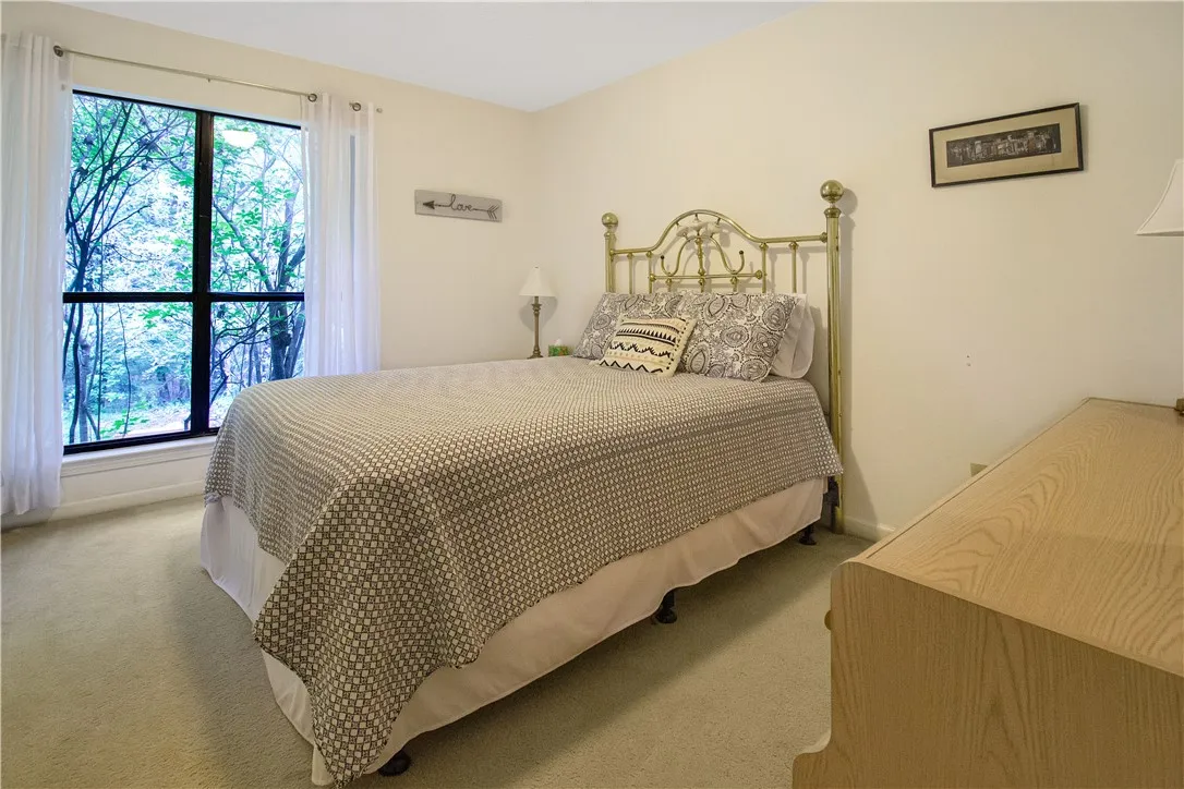 A naturally illuminated bedroom with verdant outdoor views offers a serene retreat.