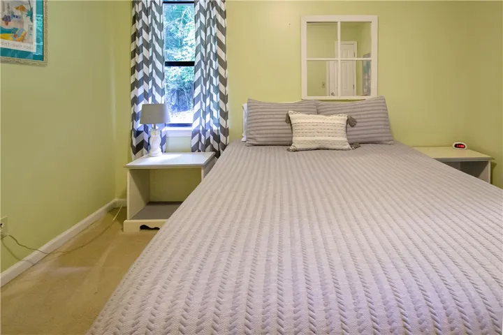 A tranquil bedroom features a soft color palette and a well-lit window overlooking lush greenery.