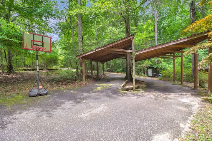 Discover a private retreat with ample parking beneath rustic carports, nestled amidst verdant surroundings.