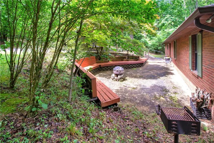 An inviting backyard patio features built-in wooden benches surrounding a stone fire pit, perfect for outdoor gatherings.