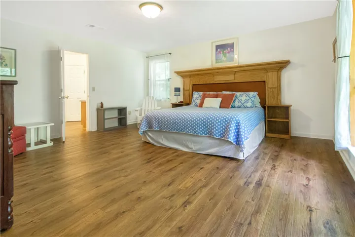 Natural light illuminates the rich hardwood-style flooring in this generously sized bedroom.