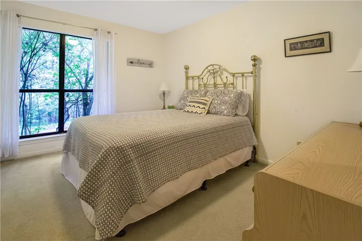 A naturally illuminated bedroom with verdant outdoor views offers a serene retreat.