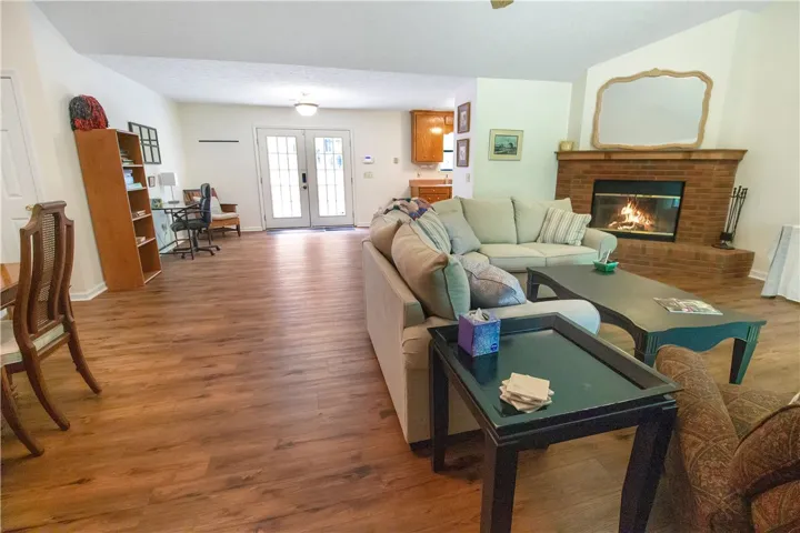 An inviting hearth with a crackling fire anchors this generous living area with warm wood flooring.