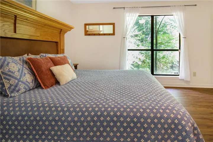Well-lit sleeping quarters with rich wood flooring and a refreshing tree-filled vista.